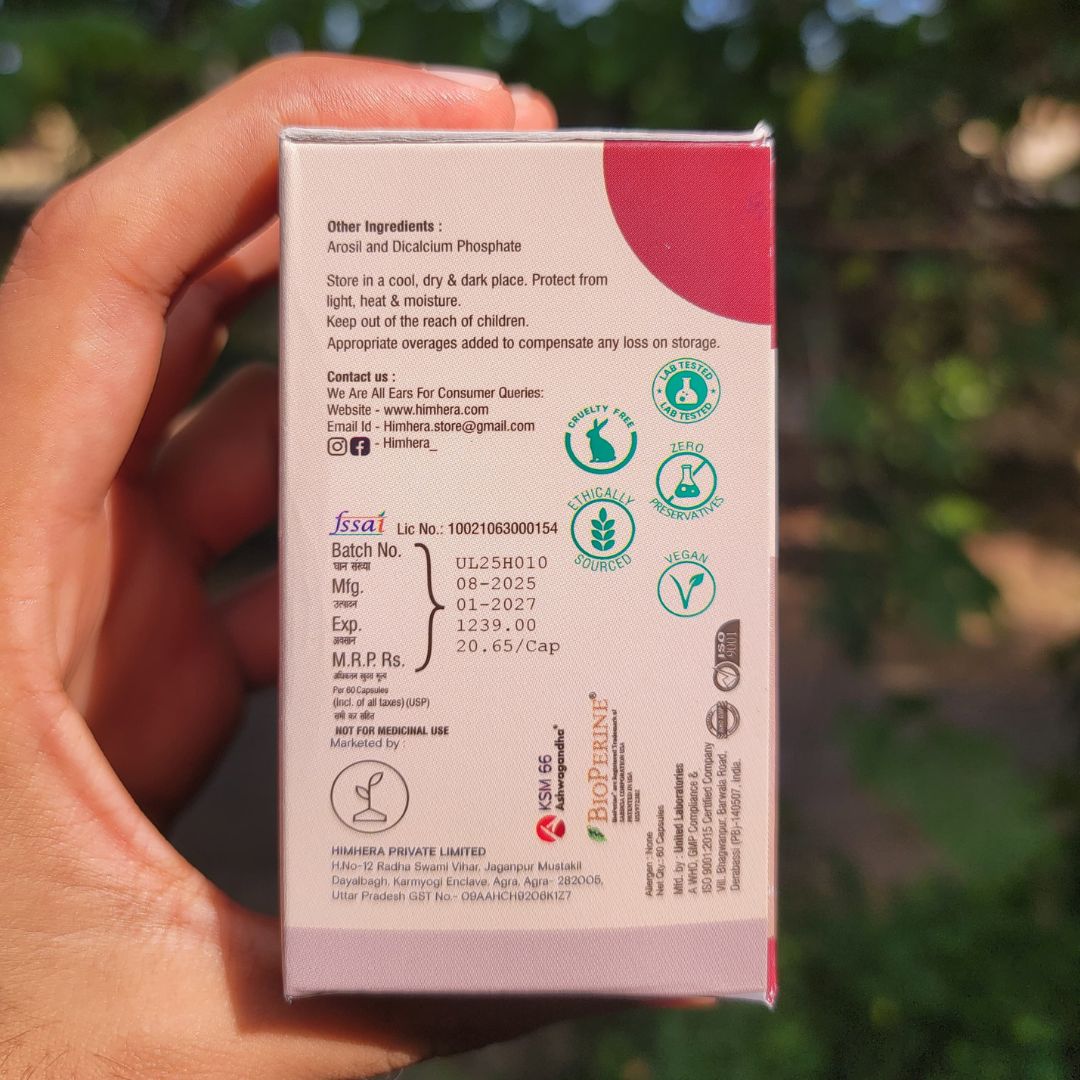 Hand holding a small rectangular box with text and logos against a blurred natural background